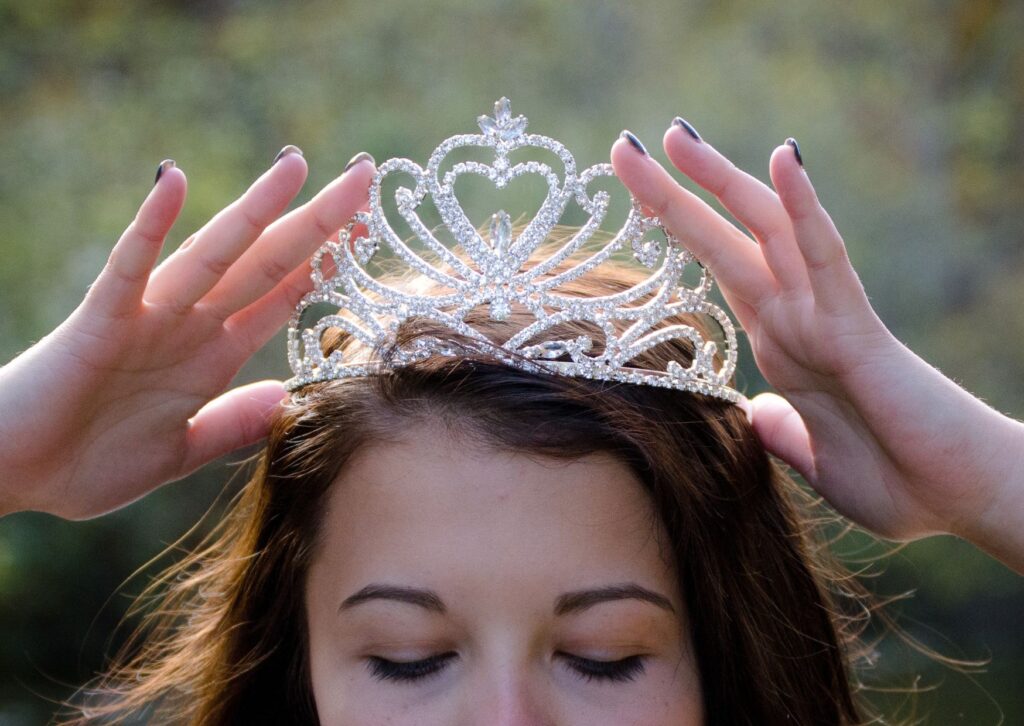 A lady putting a crown on her head