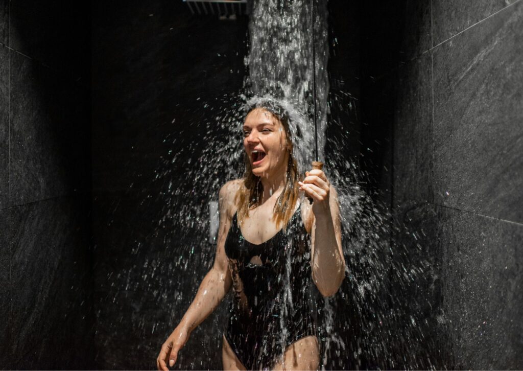 lady taking a cold shower to improve wellness