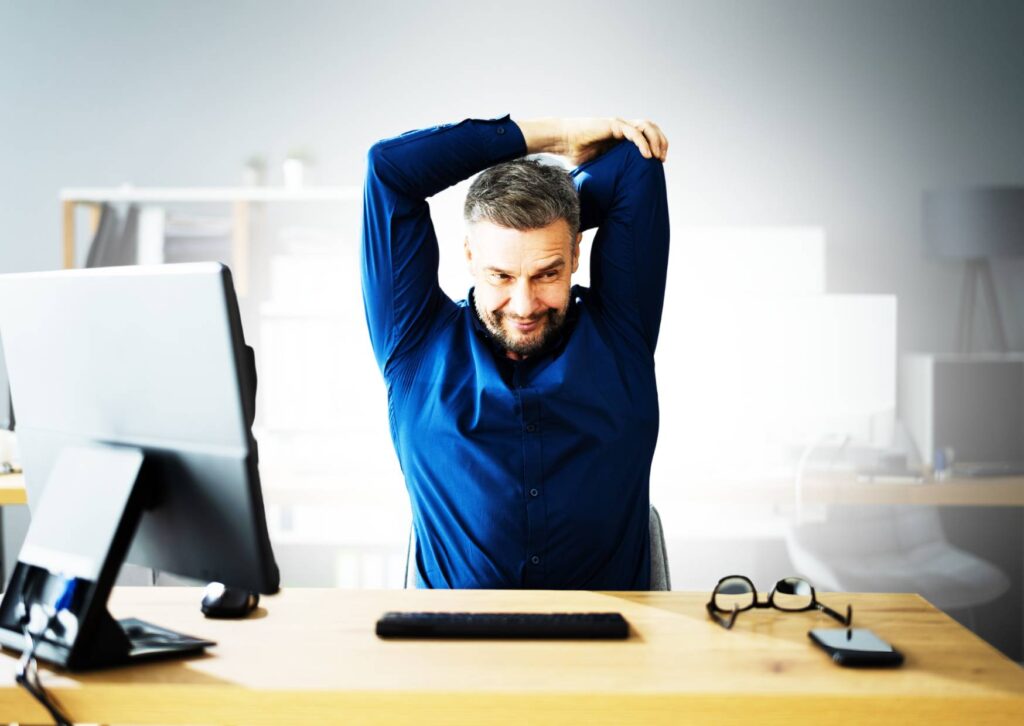 man-stretching-at-his-desk-taking-a-break-from-work
