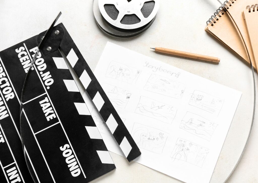 Movie-Clapper-with-Storyboard-Notebooks-and-Film-Reel-on-Light-Background