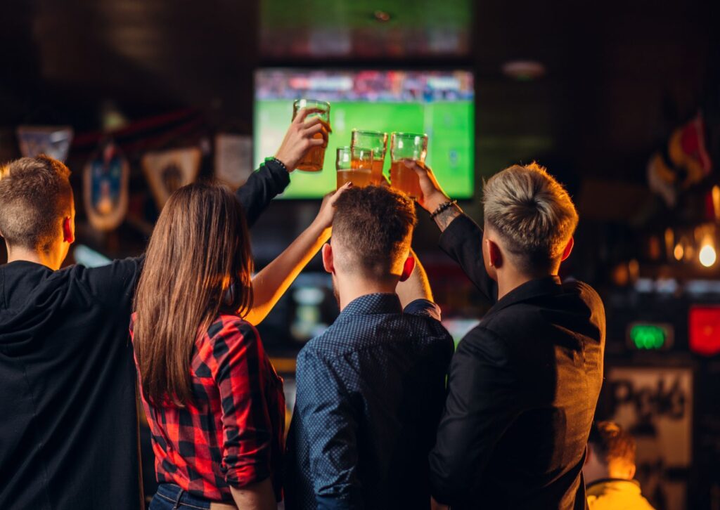 people-at-a-sports-bar-drinking-beer-and-watching-sports-on-a-big-tv