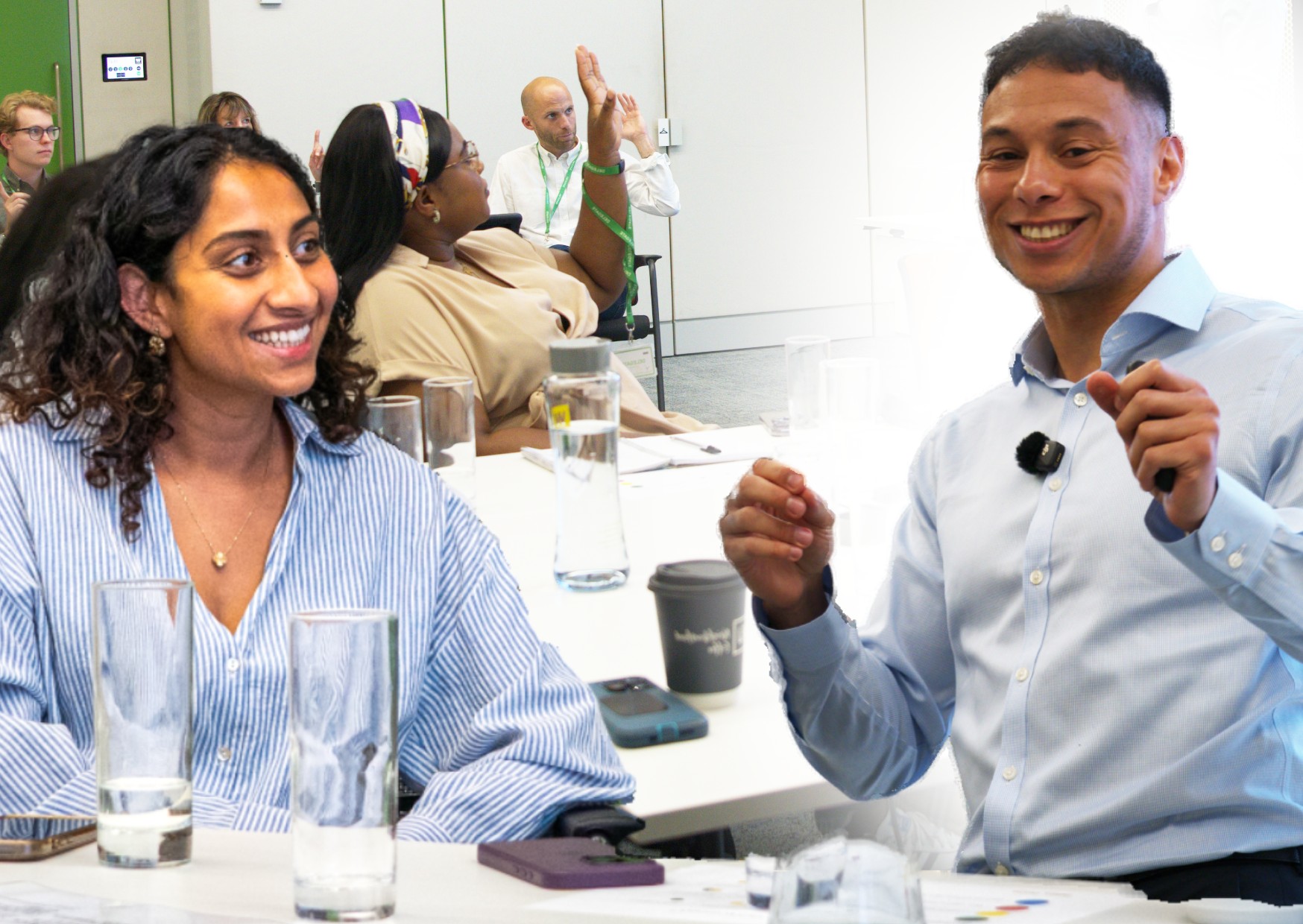 employees-at-a-corporate-lunch-and-learn-smiling-interacting-with-hands-up-with-a-facilitator-who-is-smiling
