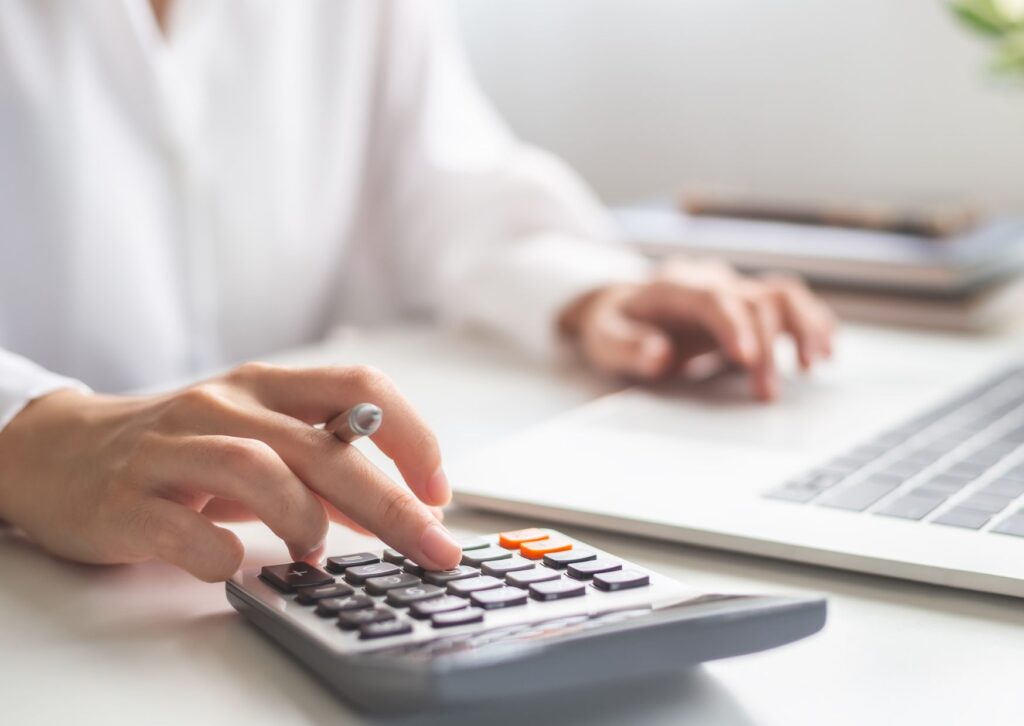 female hands on a typing on a calculator working out the cost of a team meeting