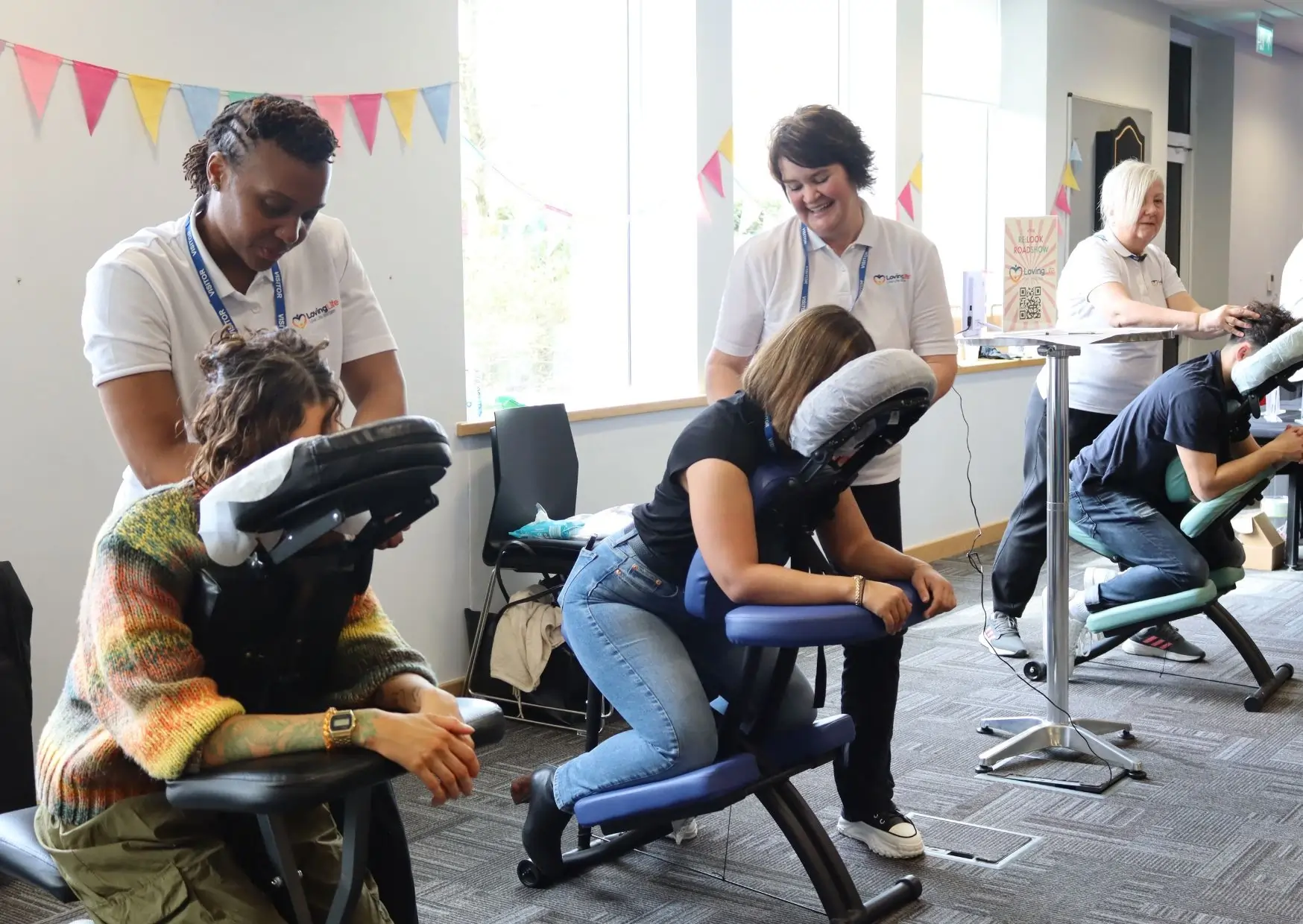 Massage therapists delivering on-site chair massage in a company office building.