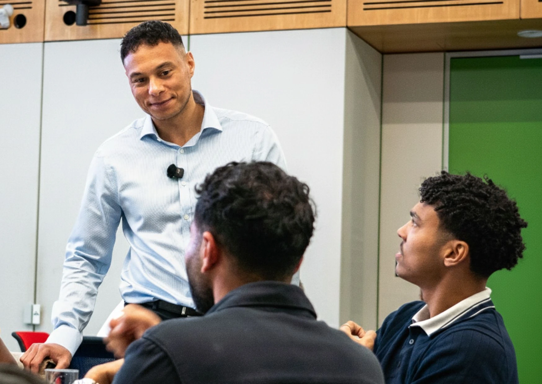 Men smiling and talking during a workshop discussion.